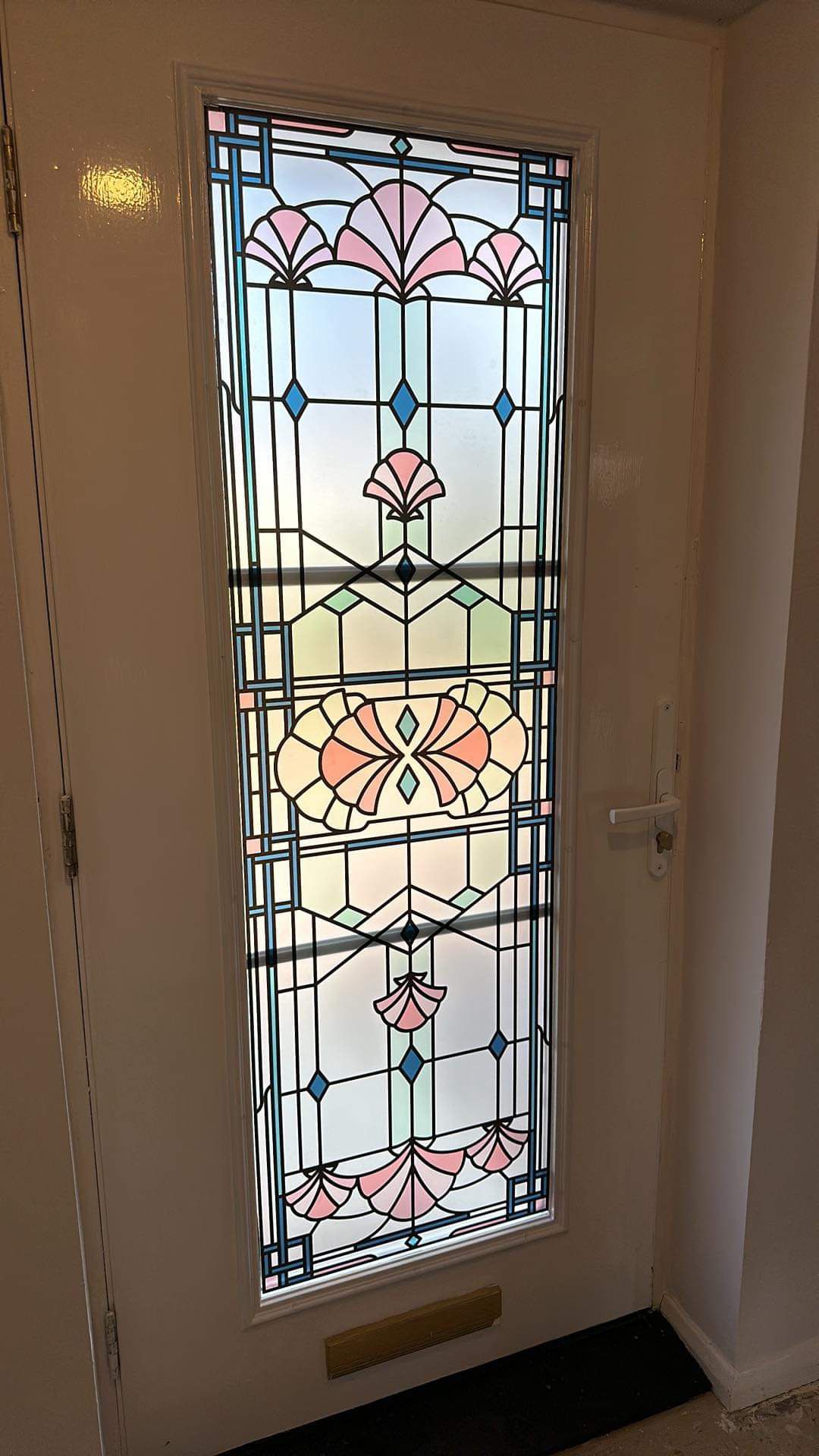 A large print of the beatrice stained glass film installed in a glass pane door in a frosted background for privacy.jpg